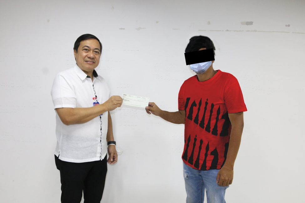 Assistant General Manager for Gaming Sector Arnel A. Casas (left) hands over the check to the new Grand Lotto